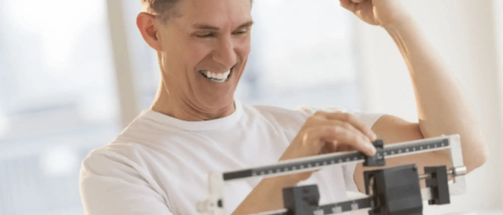 Man celebrating on a scale, indicating weight loss success.